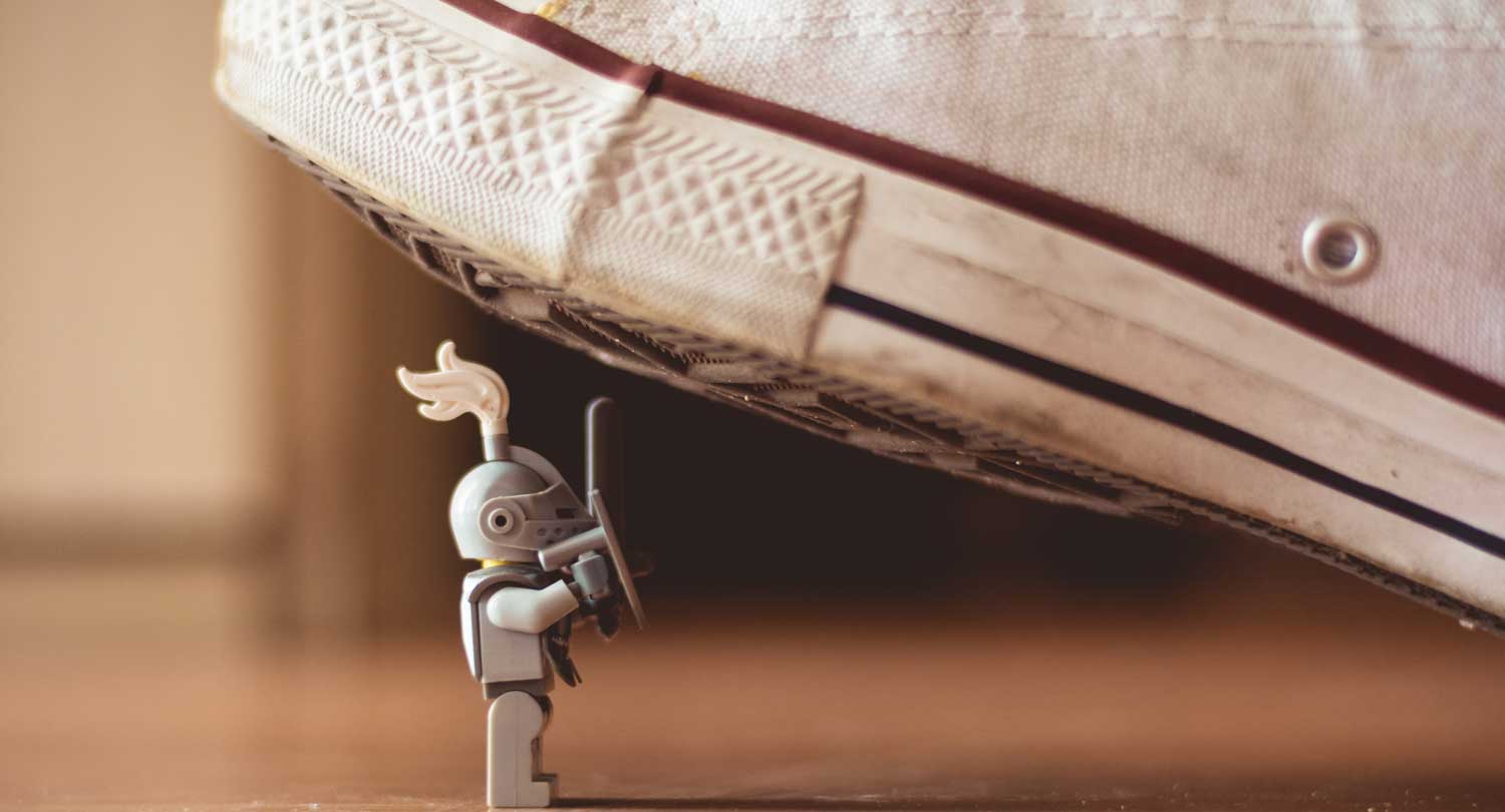 Lego figure of a knight underneath canvas shoe