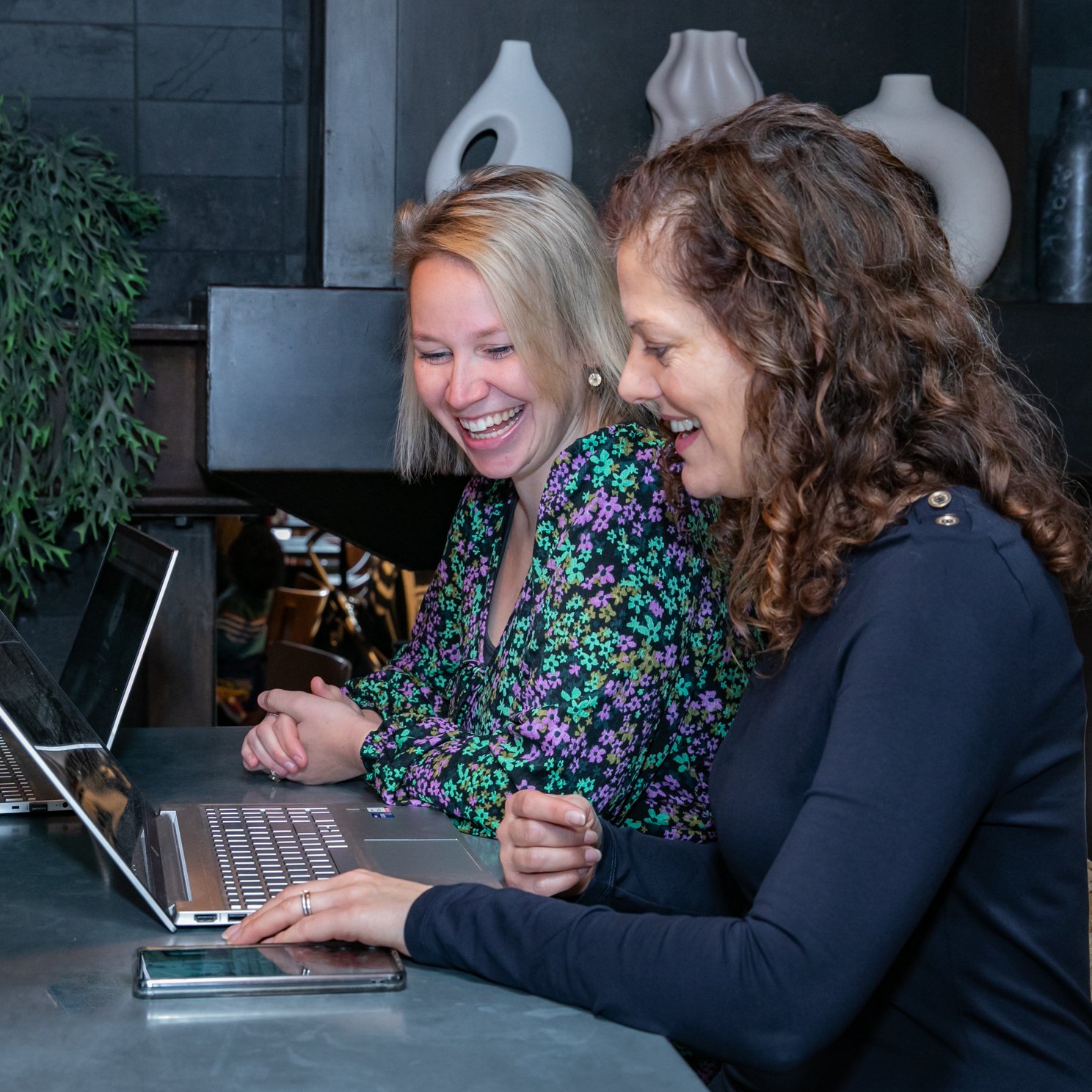 Two people smiling at laptop screen.