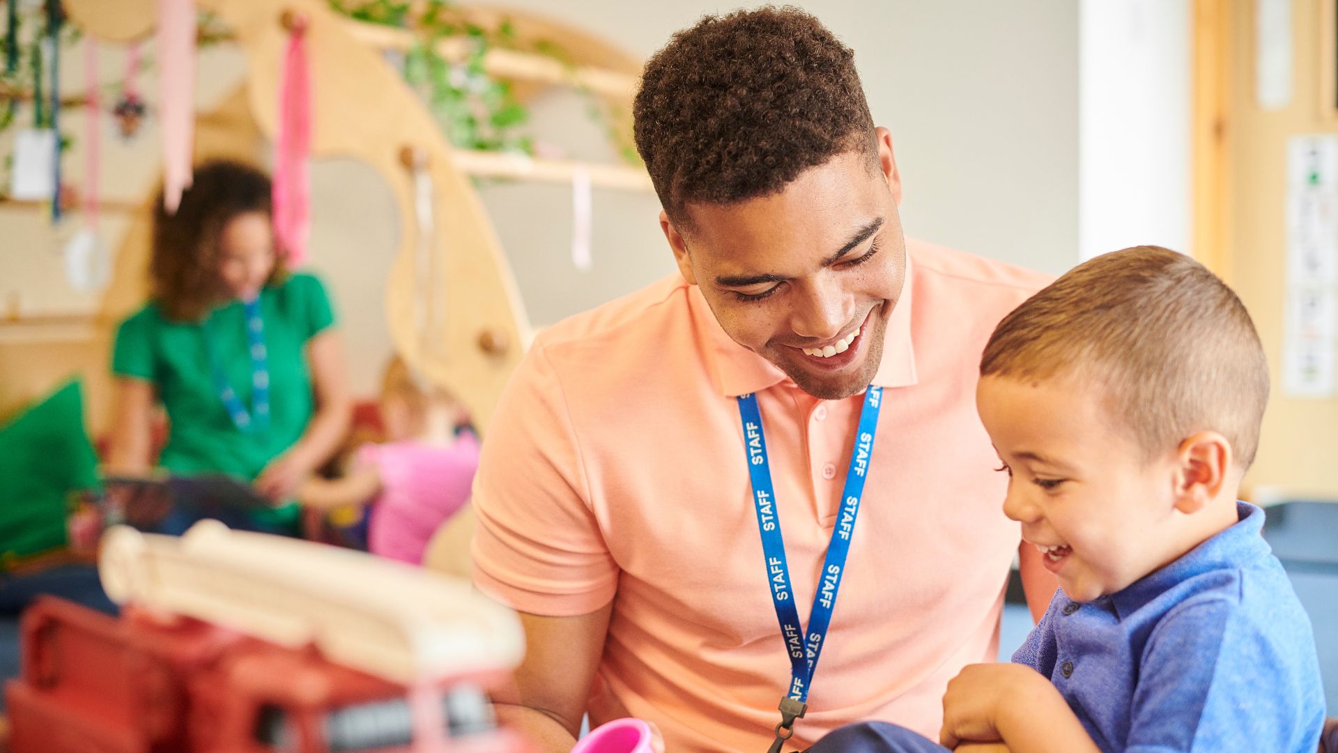 A male early years practitioner with a young boy at nursery.